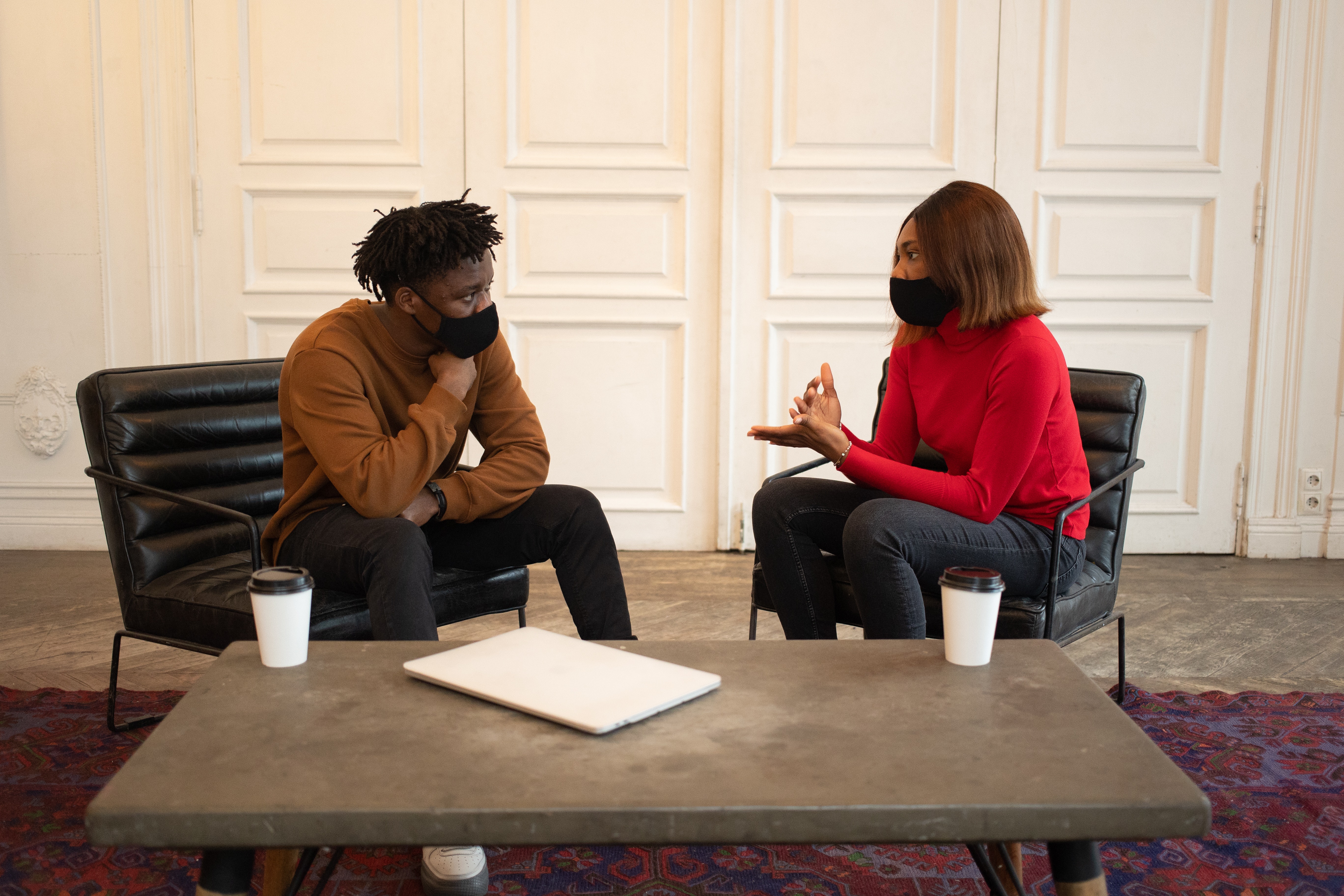 A man and a woman meeting face to face wearing masks