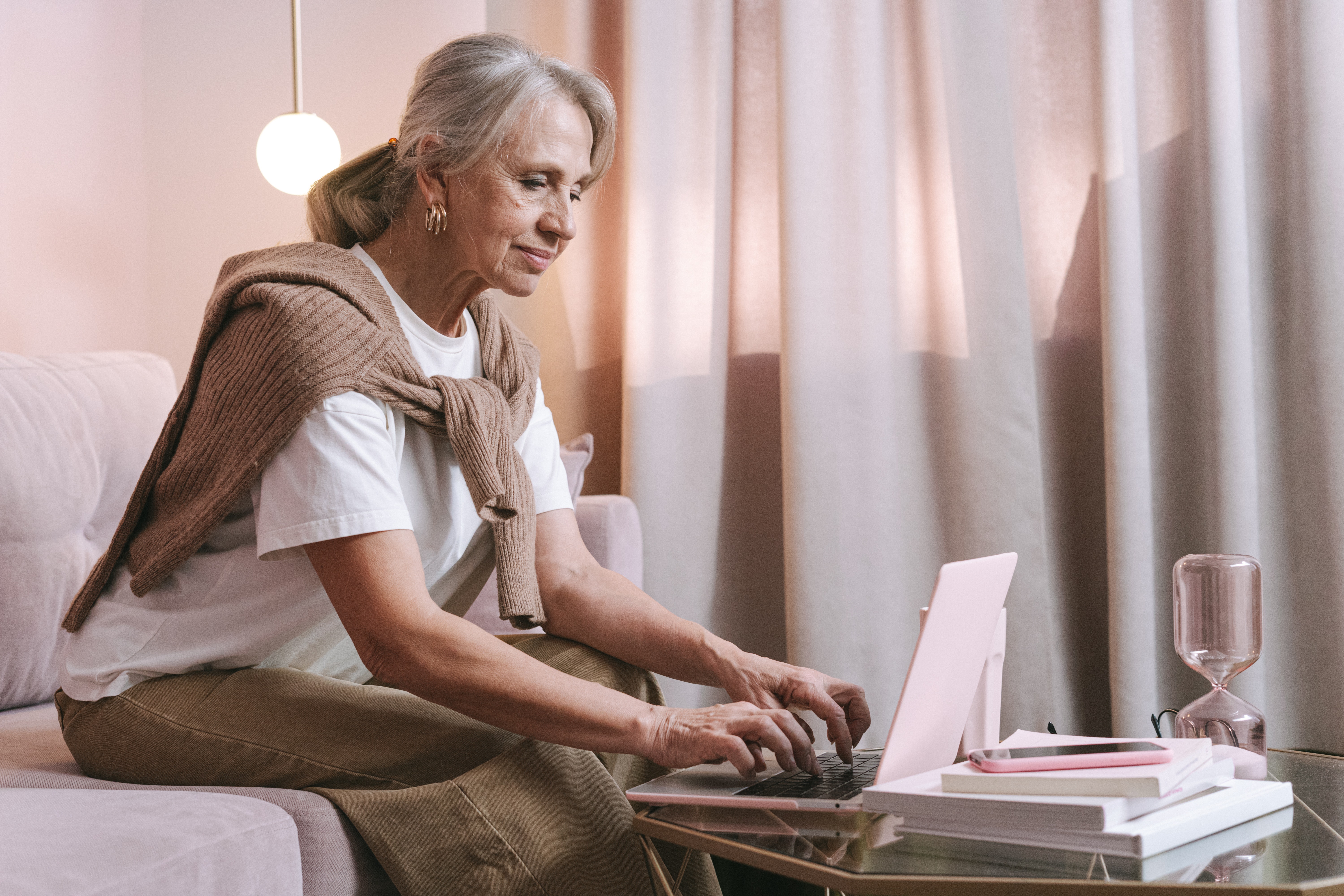 Woman sitting drinking coffee in kitchen looking at paperwork